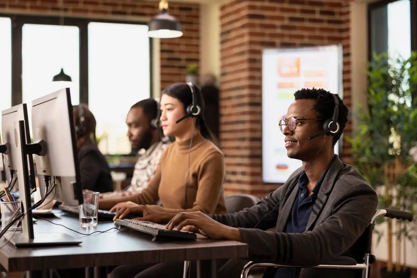 Чернокожий мужчина в инвалидной коляске пользуется компьютером.